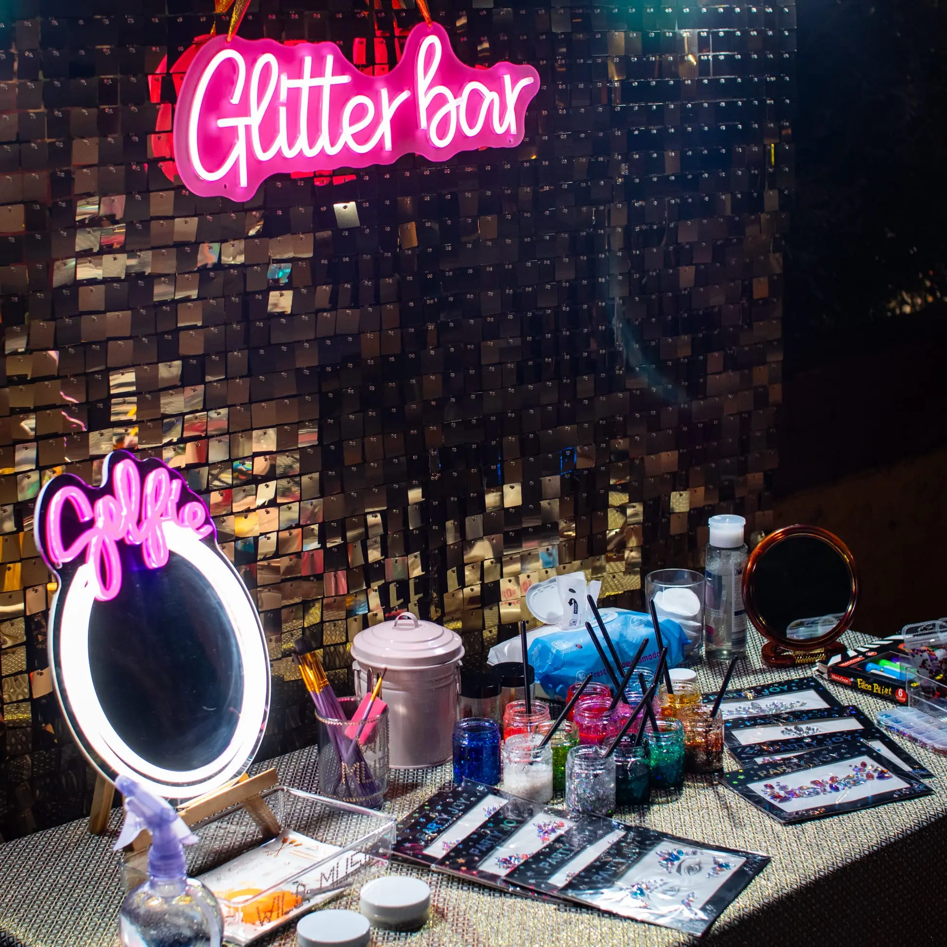 Mesa de Glitter Bar con maquillaje, purpurina y accesorios neón para barra libre en bodas Wild Music