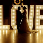 Silueta de novios posando frente a unas espectaculares letras gigantes luminosas de LOVE, alquiladas para su boda con Wild Music Sevilla.