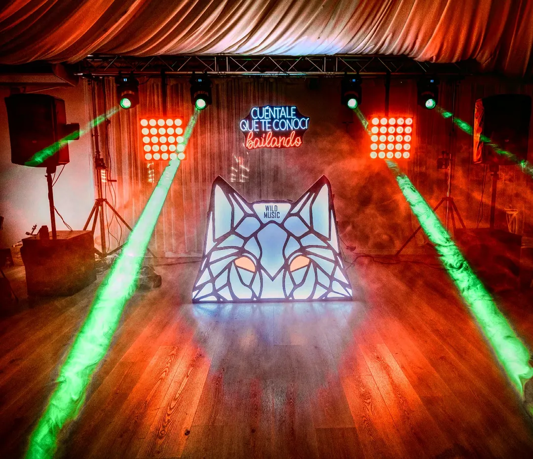 Montaje Set Premium de Wild Music con cabina iluminada, neón decorativo, cabezas móviles, efectos Matrix y sonido profesional para bodas tipo festival.